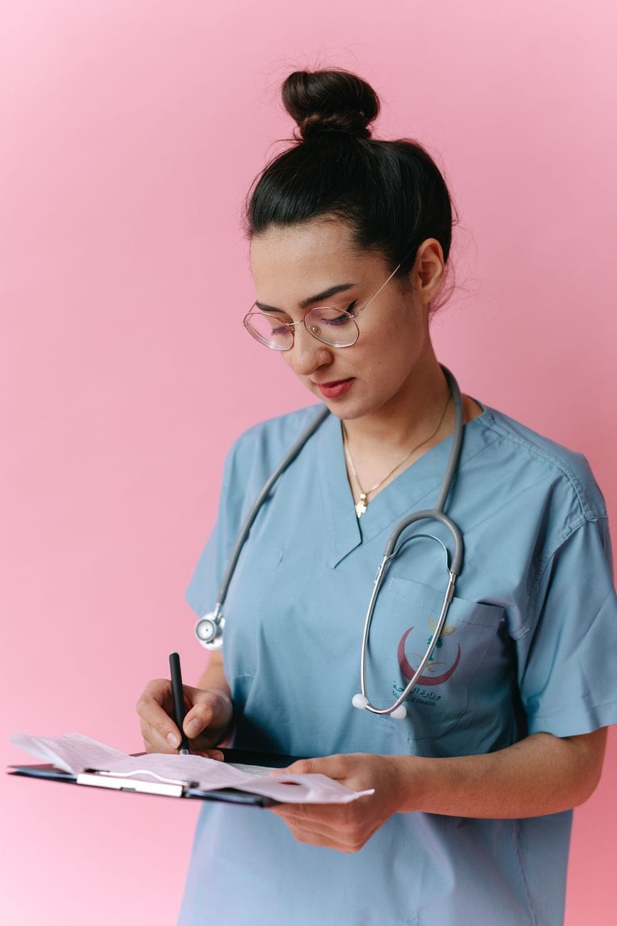 Healthcare professional in scrubs holding a clipboard