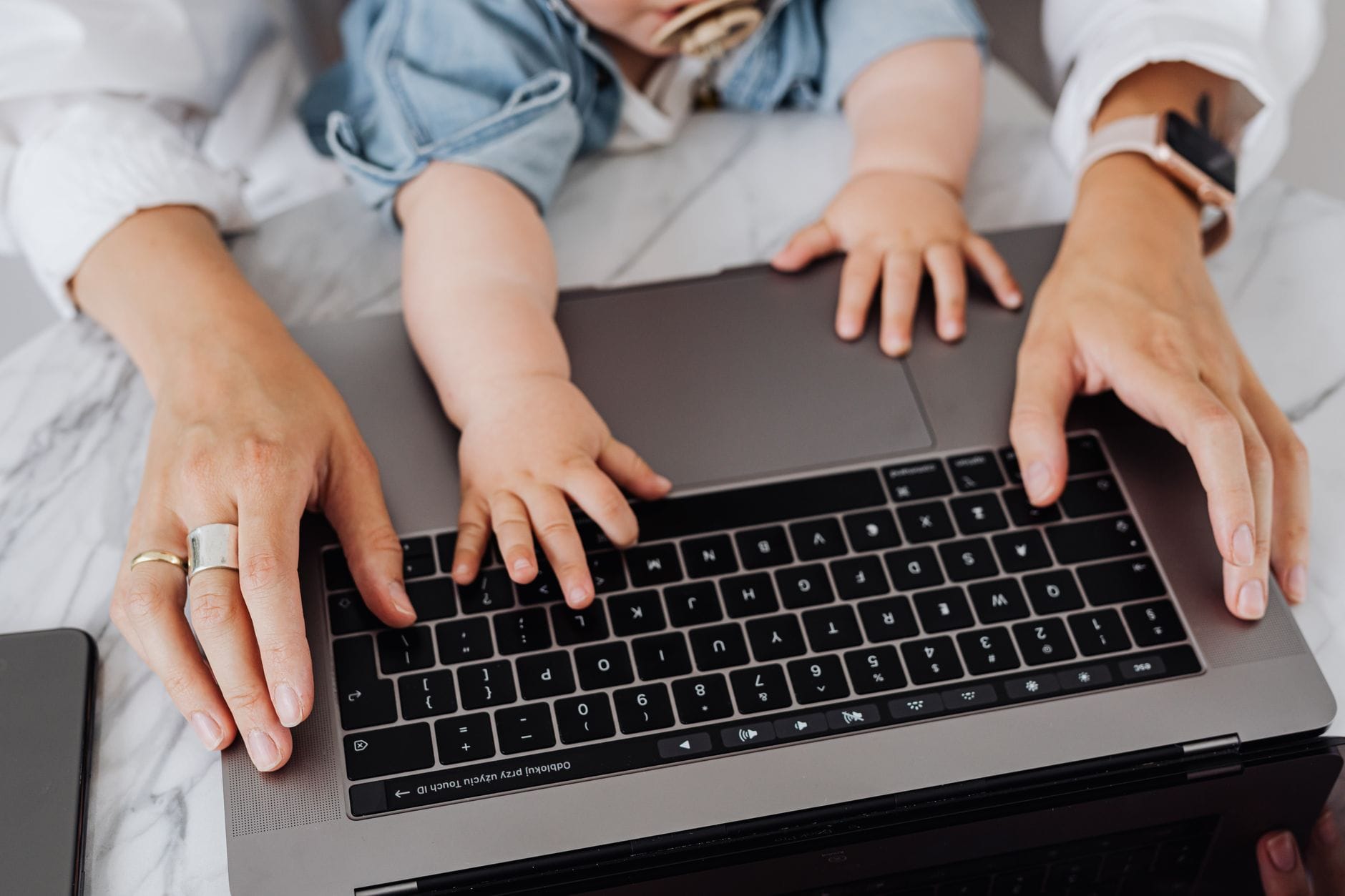 Parent and child hands on a laptop keyboard working from home