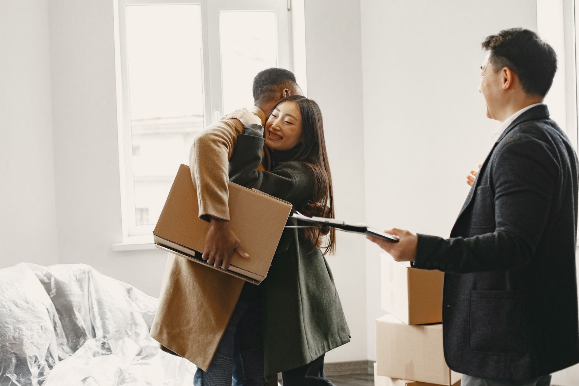 Real estate agent handing moving box to a couple in a new home
